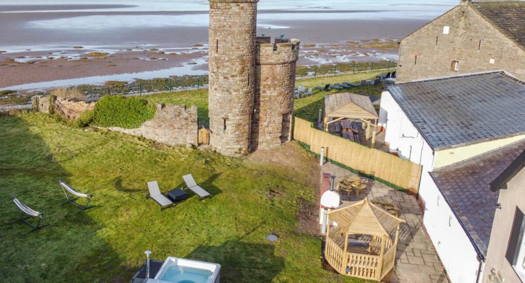 Coastal party house garden with hot tub and stone tower overlooking Morecambe Bay, ideal for a Morecambe stag do.