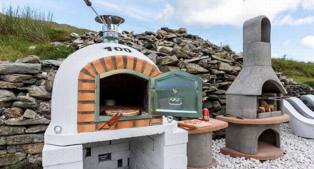 Outdoor BBQ station and large stone fire pit at the Mountaintop Marvel Lake District hen party house