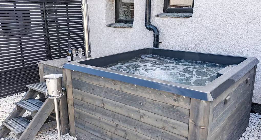 Outdoor hot tub on the patio with seating area at the Mountaintop Marvel Lake District luxury hen house