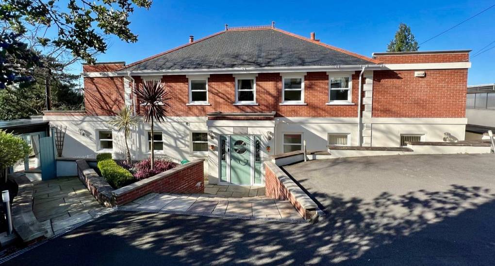 Large brick hen party house exterior with paved driveway and entrance ramp at Cathedral View near New Forest.