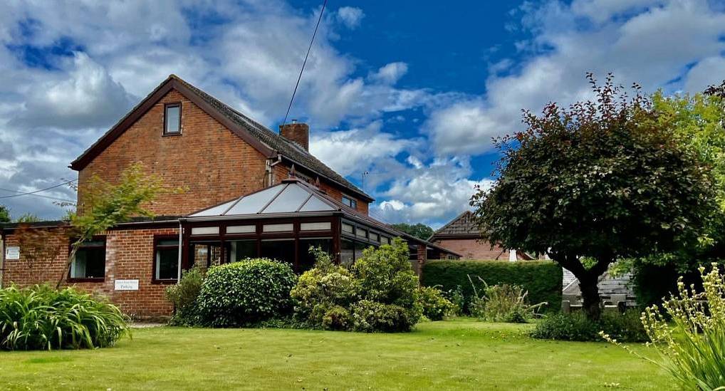 Red brick house exterior with dark glass conservatory and manicured lawn at Forest Tree house in the New Forest.