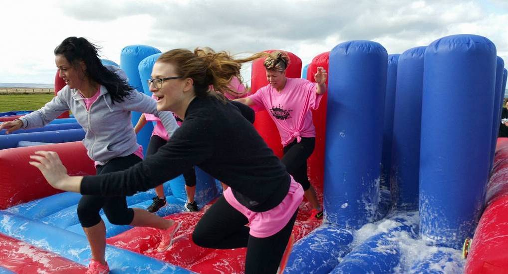 Group of hens enjoying inflatable obstacle games during a Newcastle hen do knockout package.