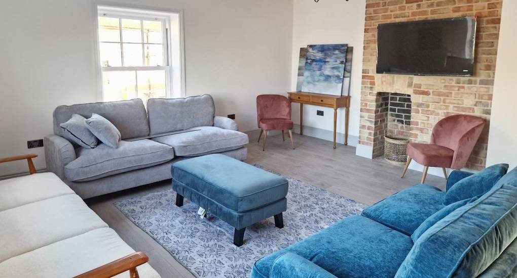 The stylish living room with velvet sofas at Coastal Charm, a coastal Norwich hen party house near the beach.