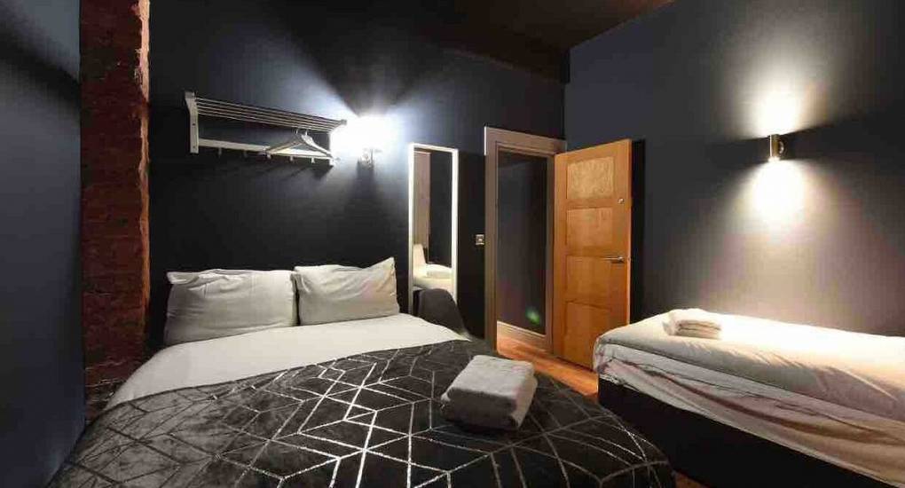 Stylish bedroom area with dim lighting and showing a double and single bed