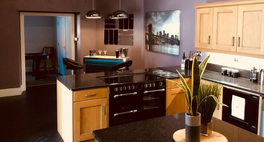 Open plan kitchen with island in monochrome colours and wooden cupboards