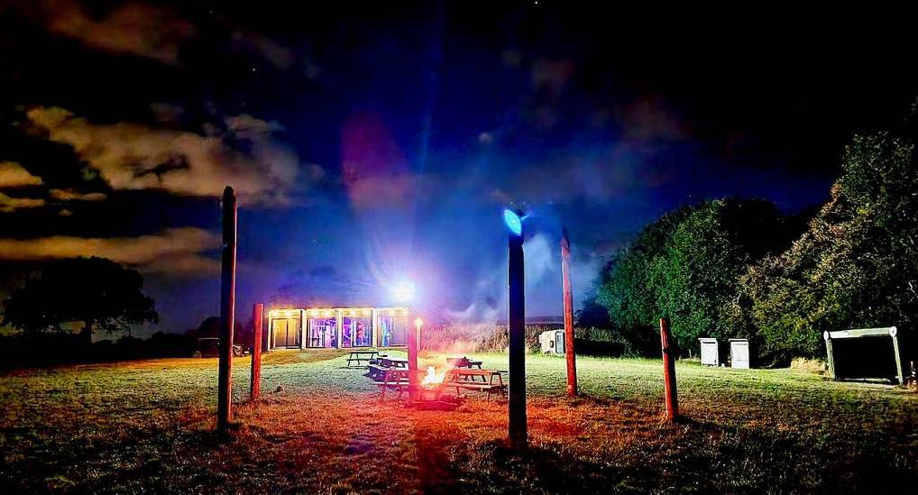 The outdoor fire pit and lit festival barn at Mini Fest, unique hen party glamping near Oxford.
