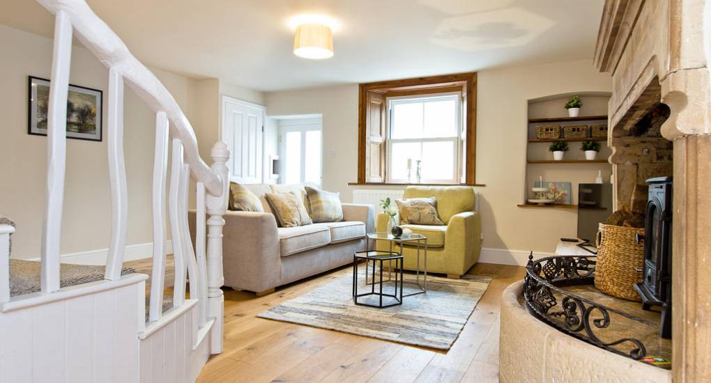Cosy lounge in Star House at Peak Star featuring a traditional log burner and an original stone fireplace.