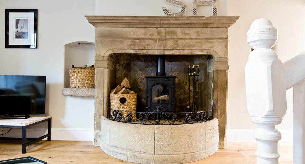 Original stone fireplace with a traditional log burner in Star House at Peak Star, creating a charismatic and traditional vibe.