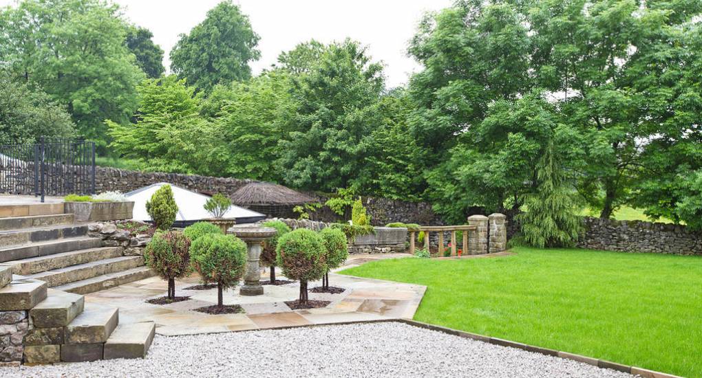 The stunning private gardens and stone terrace at Peak Star, featuring panoramic views of the Taddington countryside.