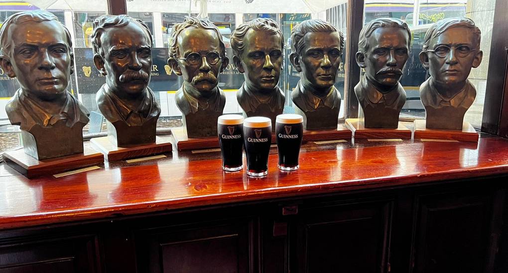 Three perfect pints in front of busts of Guinness VIPs