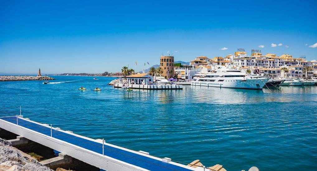 Luxury yachts in Puerto Banus marina with white coastal buildings, sunny backdrop for a Puerto Banus stag do.