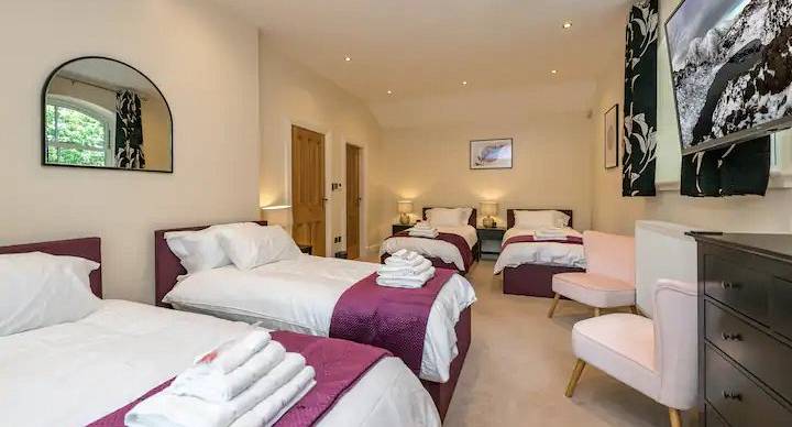 Large bedroom with four made up single beds 