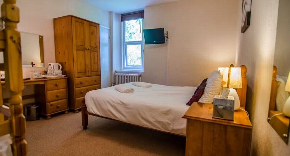A single bedroom at River View Lodge with a wardrobe, bedside table, and desk, ideal for hen weekend accommodation.