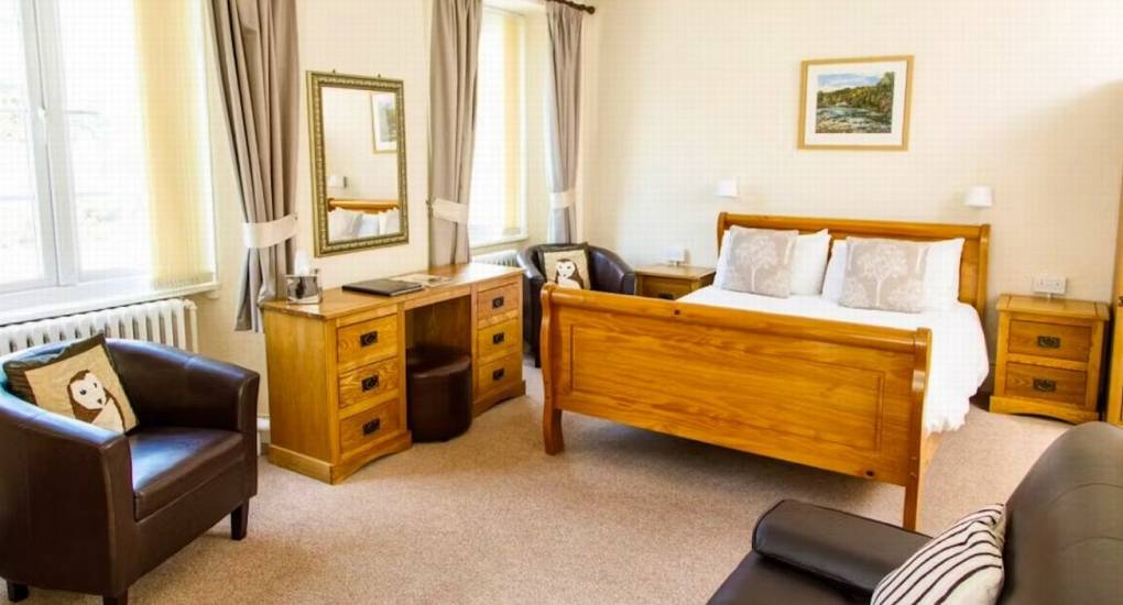 A twin-bedded room at River View Lodge with a large wooden dresser and comfortable armchairs, perfect for a hen party stay.