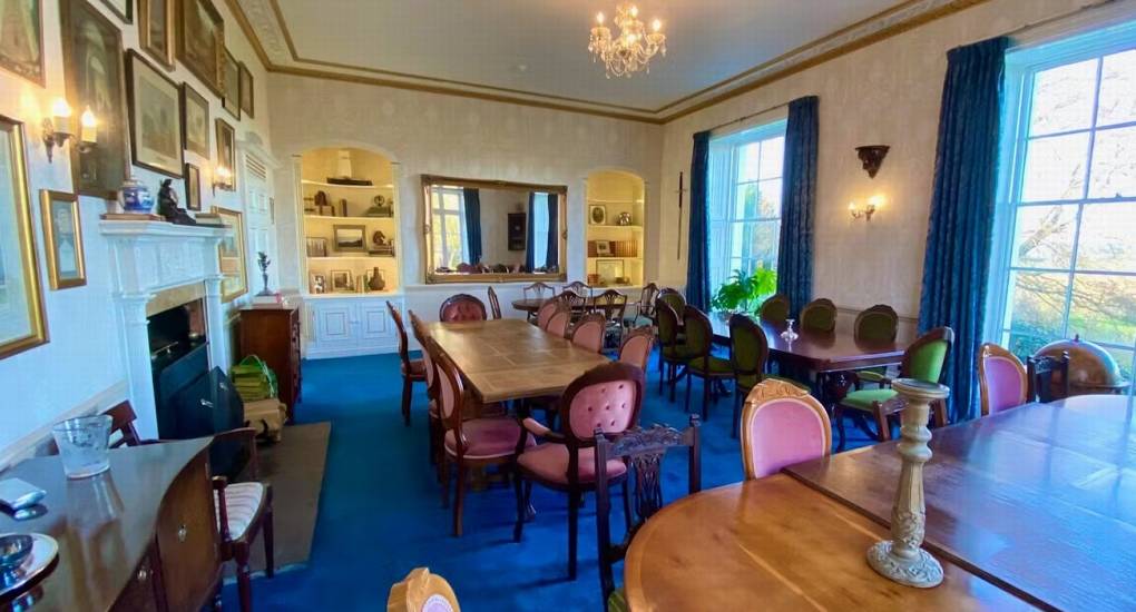 A view of the spacious dining room at this Herefordshire hen party mansion, with a fireplace and large windows.