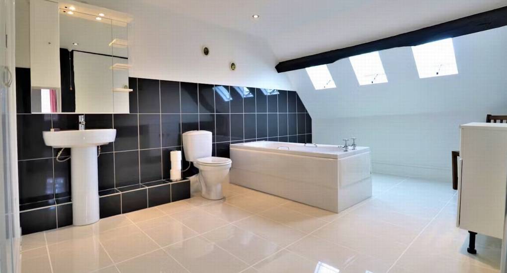 A spacious and modern bathroom with a large bathtub and skylights at Rivers Countryside Mansion, providing comfort for a large hen party.