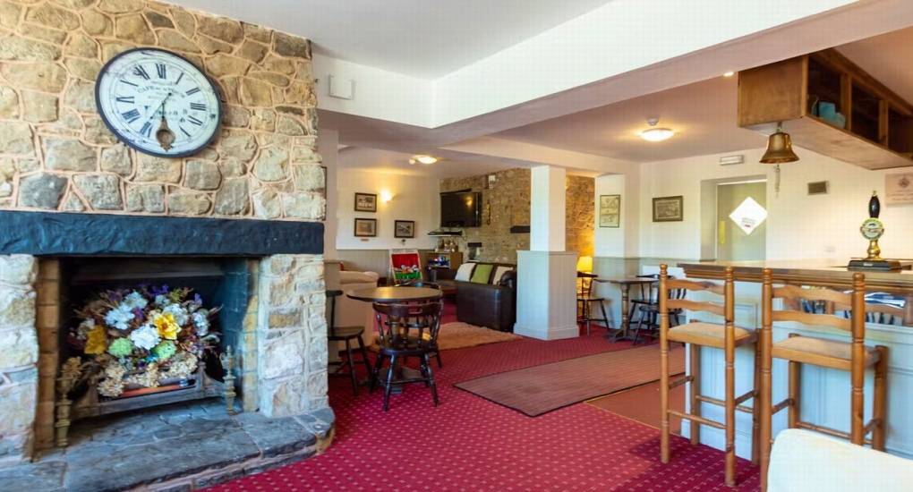 The welcoming private bar area and lounge at Ross Lodge Gloucestershire, featuring a stone fireplace and seating for the hen do accommodation that sleeps 26.