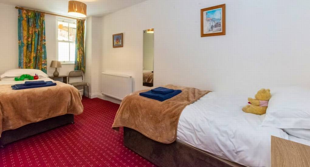 A cozy twin bedroom at Ross Lodge Gloucestershire with warm brown bedspreads, offering flexible sleeping for a large hen do group that sleeps 26.