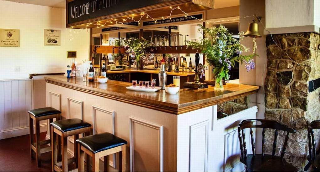 A close-up view of the wooden bar area at Ross Lodge Gloucestershire, complete with bar stools and taps, highlighting the Hot Tub & Games Room features of this Gloucestershire Hen Do Accommodation.