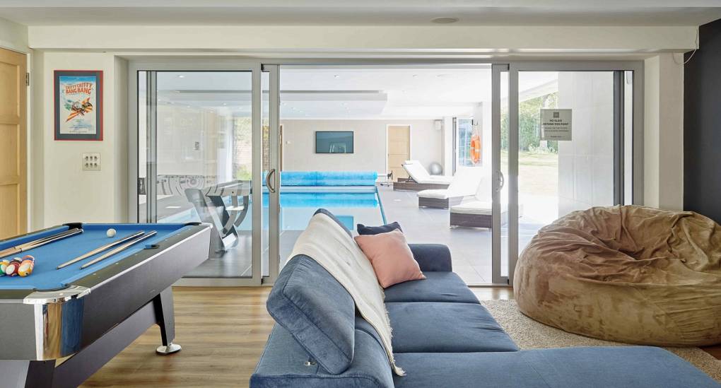 Social games room with pool table at Spa Town, featuring bi-fold doors leading to the luxury indoor heated pool.