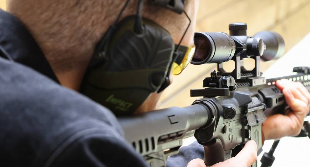 Stag taking aim with a live fire rifle on a range in the UK