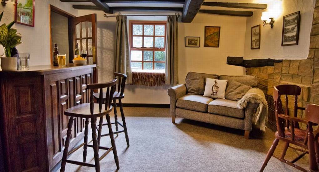 The private wooden bar and seating area at Standing Barn Gloucestershire, featuring stone walls and exposed beams, creating a perfect Party House atmosphere for groups that sleep 22.