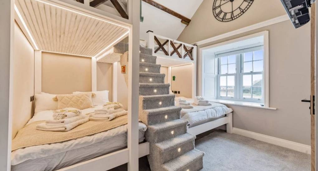 Large off white decorated bedroom with two double over bunk beds made up ready for guests