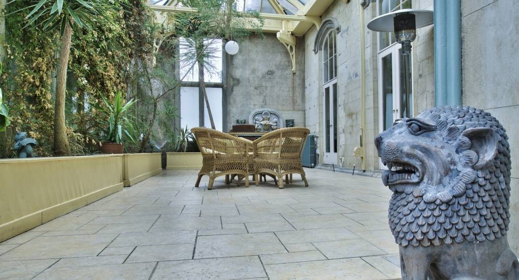 The Atrium with plants and trees on the left and lions head statue in the foreground