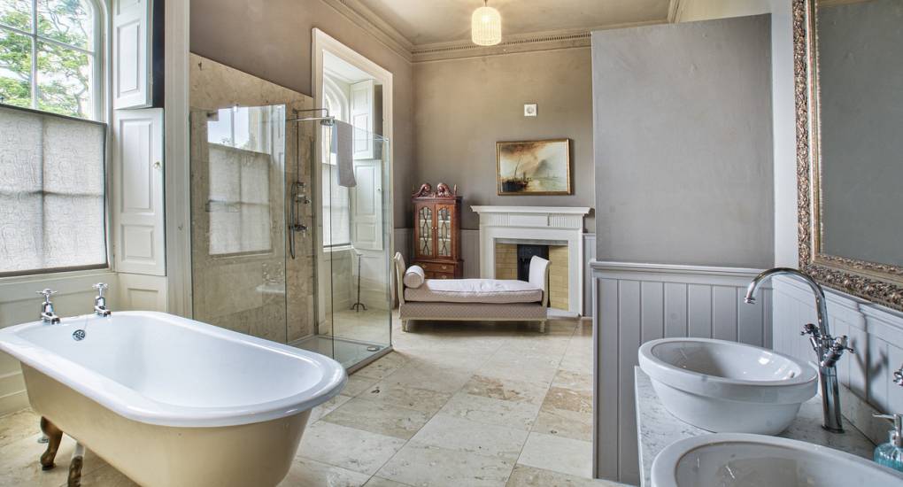 Large bathroom area at the Country Fortress Newcastle Party House with marble floors and freestanding bath