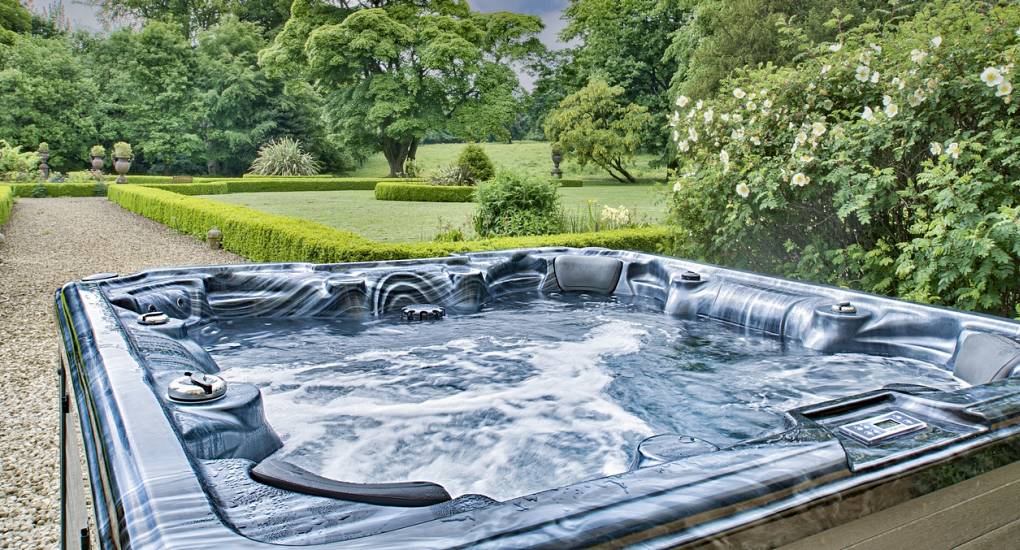 The hot tub bubbling with the well manicured gardens in the background