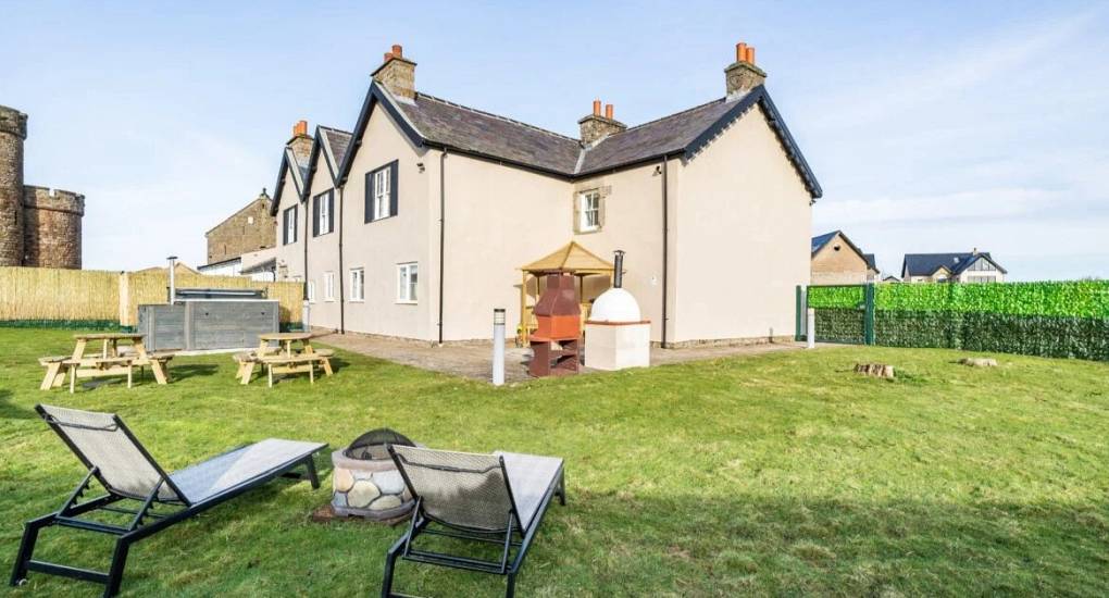 Outside view of the house across garden furniture BBQ and large firepit
