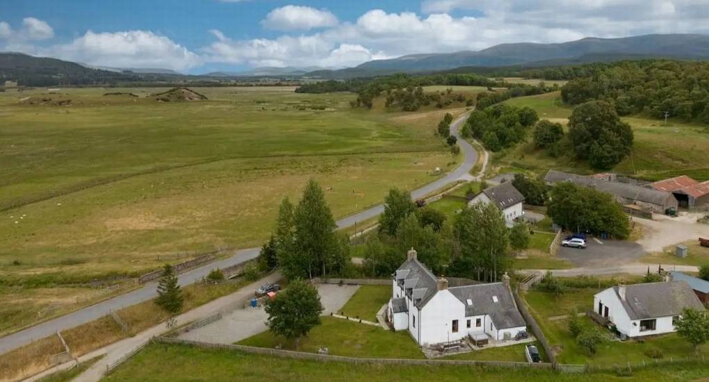 Aerial view of The Lux Lodge, a luxury Inverness hen house nestled in the Scottish Highlands with views of rolling hills and mountains.