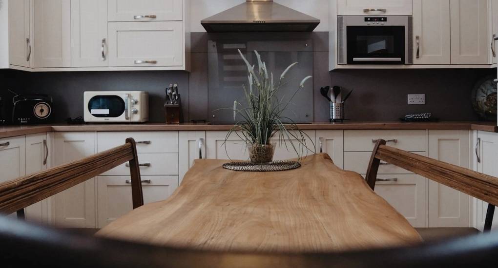 Modern white kitchen and live-edge wooden dining table at The Lux Lodge, providing spacious group accommodation for Inverness hen parties.