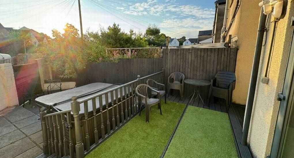 Outside decking with artificial grass covering and hot tub in the background