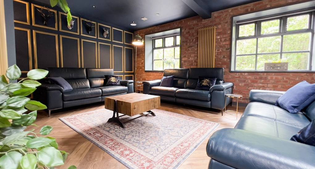 A stylish view of the open-plan living area at The Plush near Tynemouth, highlighting the industrial exposed brick, herringbone flooring, and contemporary social space for an upscale hen weekend.