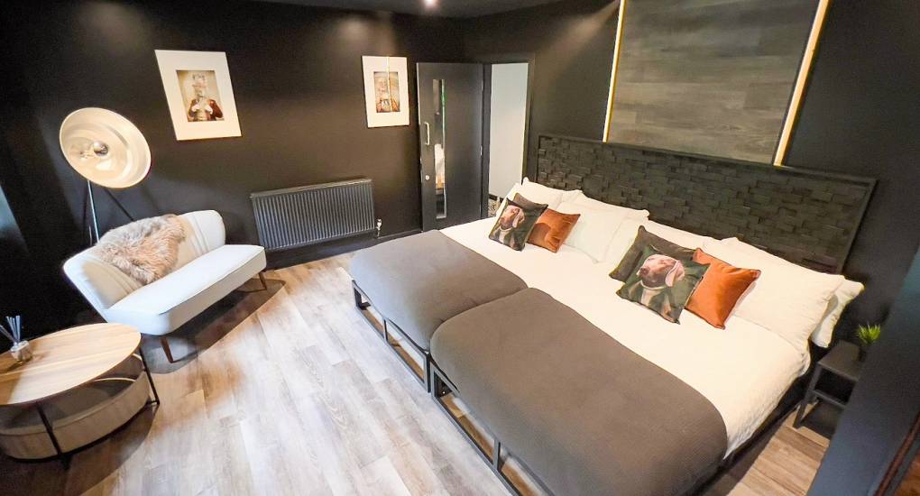 A stylish and dramatic master bedroom at The Plush, a luxury Newcastle hen do property near Tynemouth, featuring a flexible zip-and-link super king bed, modern tripod lighting, and unique animal portraits.