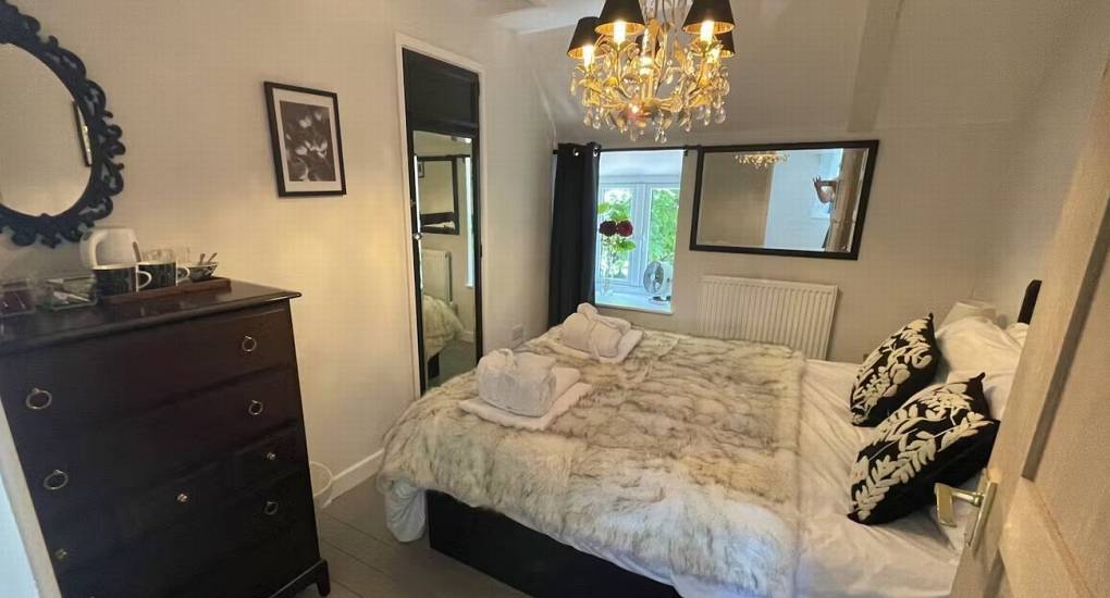 A luxurious double bedroom at The Sash House with a plush bed and stylish chandelier, perfect for a Herefordshire hen do.