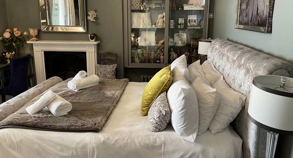A cozy and comfortable bedroom at this hen do cottage with a large bed and feature fireplace.