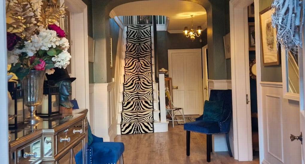 A view of the stylish hallway at The Sash House, featuring a unique zebra-print staircase runner and luxurious velvet chairs, perfect for a Herefordshire hen do cottage.