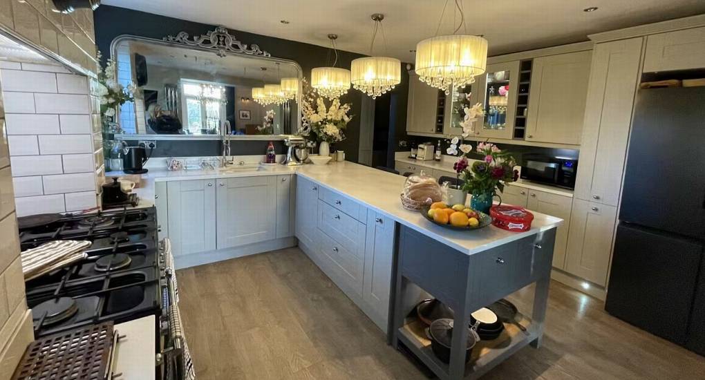 A modern and stylish kitchen at The Sash House with a spacious island, large mirror, and chandeliers, perfect for a hen do.
