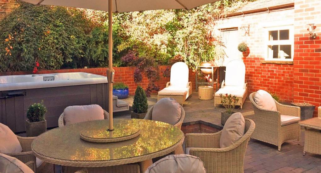 Decking area shaded by a large parasol with garden furniture and hot tub