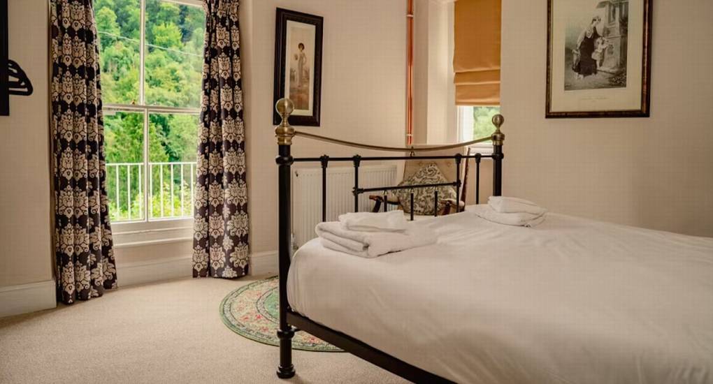 A double bedroom at The Wye House with a traditional iron bed and floor-length patterned curtains, ideal for guests at the hen party house.