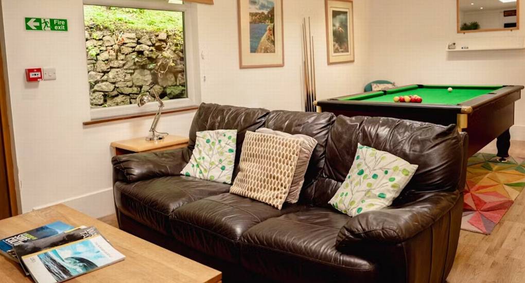 The dedicated games room at The Wye House featuring a comfortable leather sofa and a pool table, providing excellent entertainment for a Herefordshire hen party group that sleeps 22.