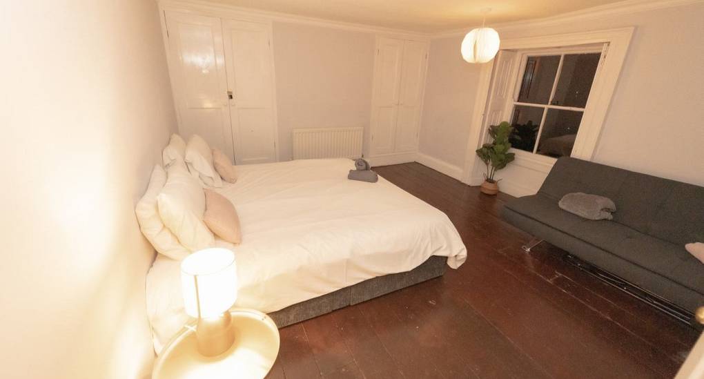 One of the six spacious bedrooms at Tranquil Escape, a detached hen do property, showcasing a king-size bed, stylish night lighting, and ample space for group prep.