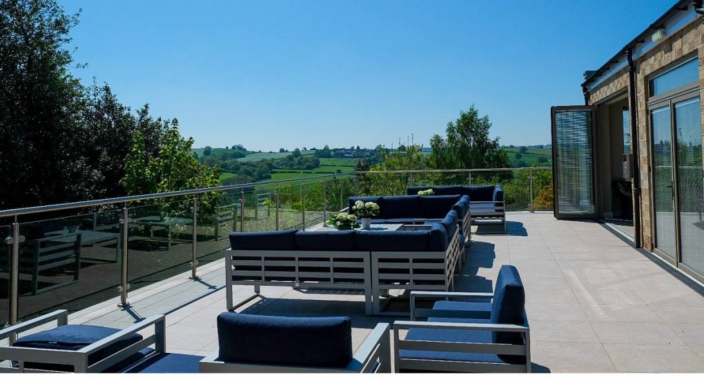 View from the terrace looing at the rolling hills of the Peak District with garden furniture in the foreground