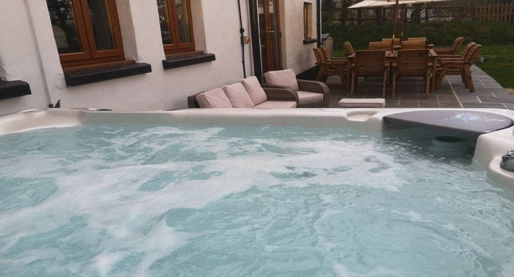 The patio hot tub and outdoor dining area at Devon Escape, a luxury Woolacombe hen party house near the beach.