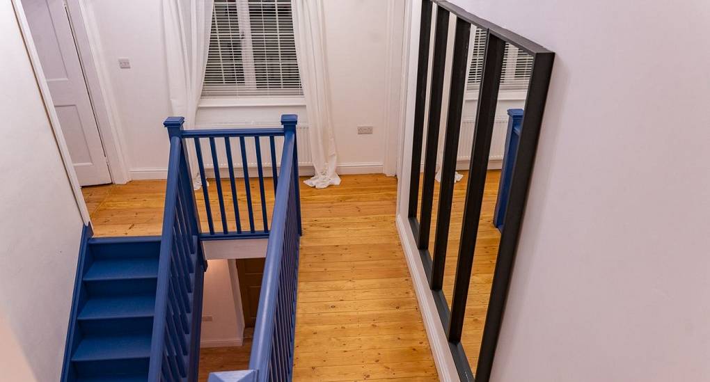 Hallway leading to bright blue stairs 