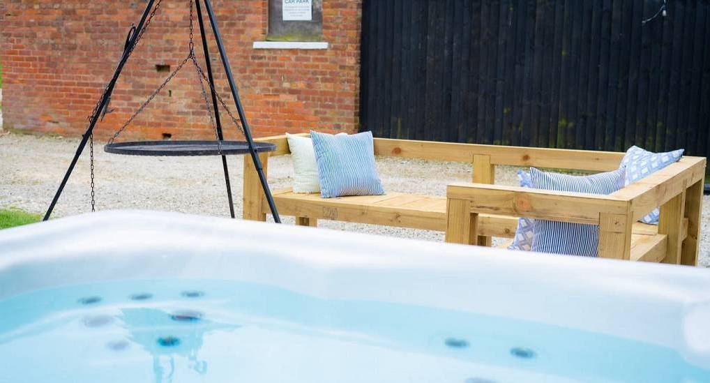 The outdoor hot tub and wooden patio bench at Rustic Charm, a York hen party house with private bar sleeping 14.