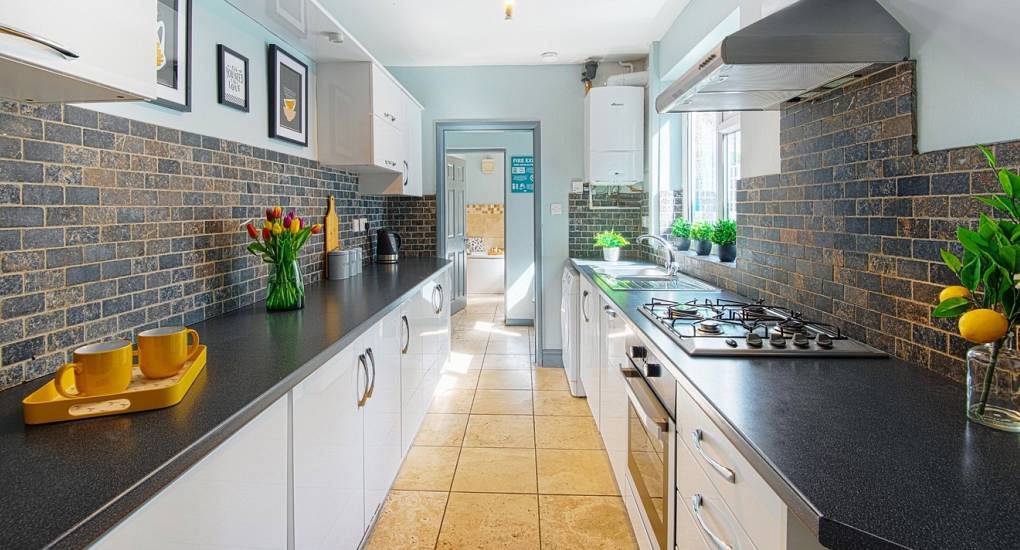 The modern galley kitchen with exposed brick tiles at The Rook, a Georgian York city centre hen party house for 12.