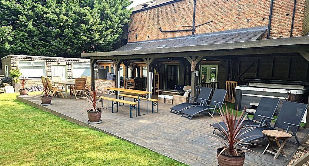 The large wooden deck patio and covered hot tub at The Stables, a converted York carriage house sleeping 24.